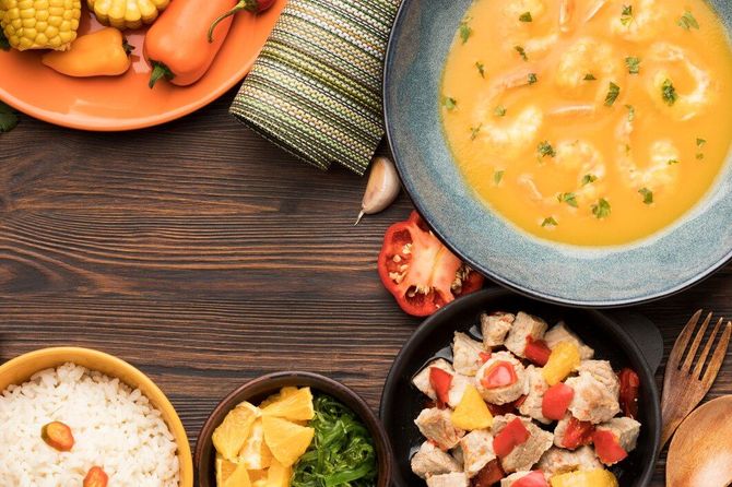 Platos variados sobre una mesa rústica, que incluyen sopa, arroz, verduras y fruta.