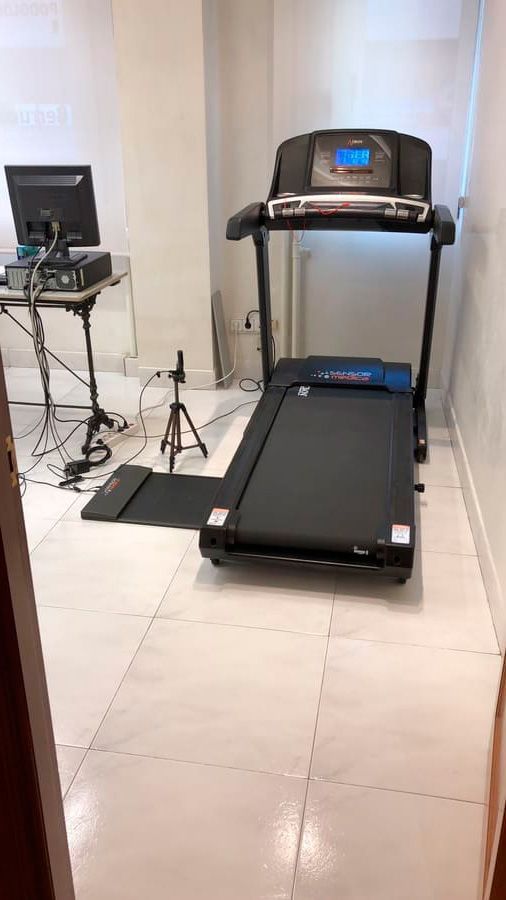 Una cinta de correr está colocada en una habitación al lado de una computadora.