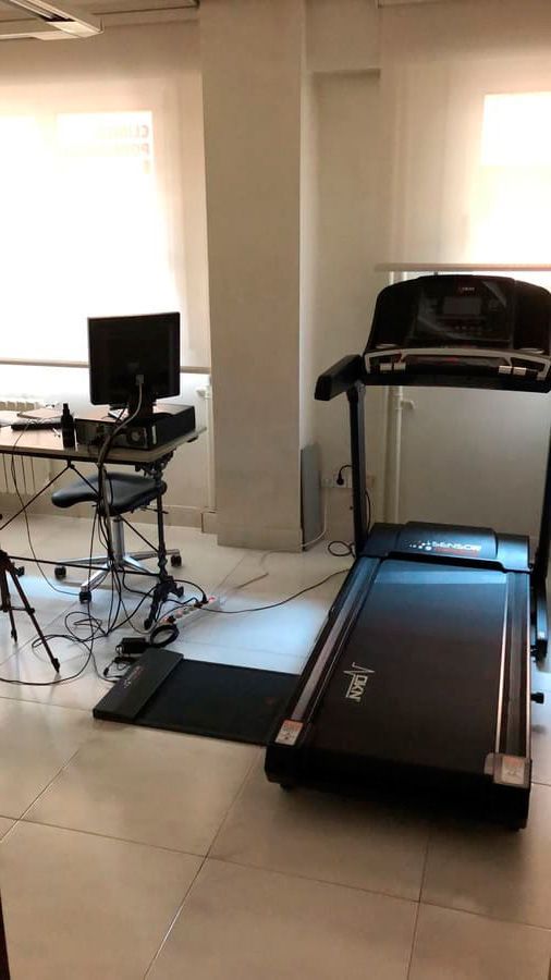 Una cinta de correr está colocada en una habitación al lado de un escritorio y una computadora.