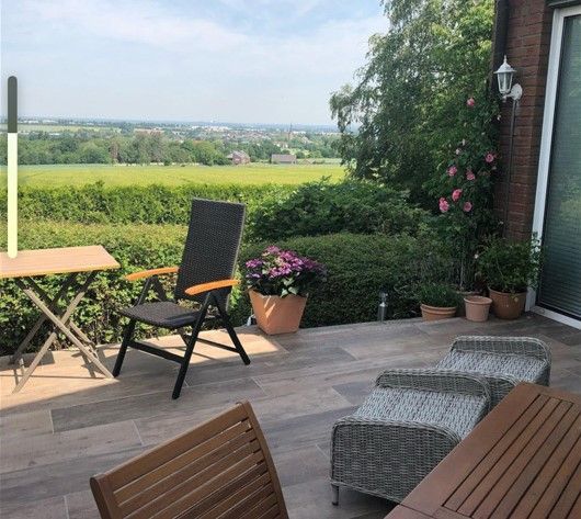 Eine Terrasse mit Stühlen, einem Tisch und Blick auf ein Feld.