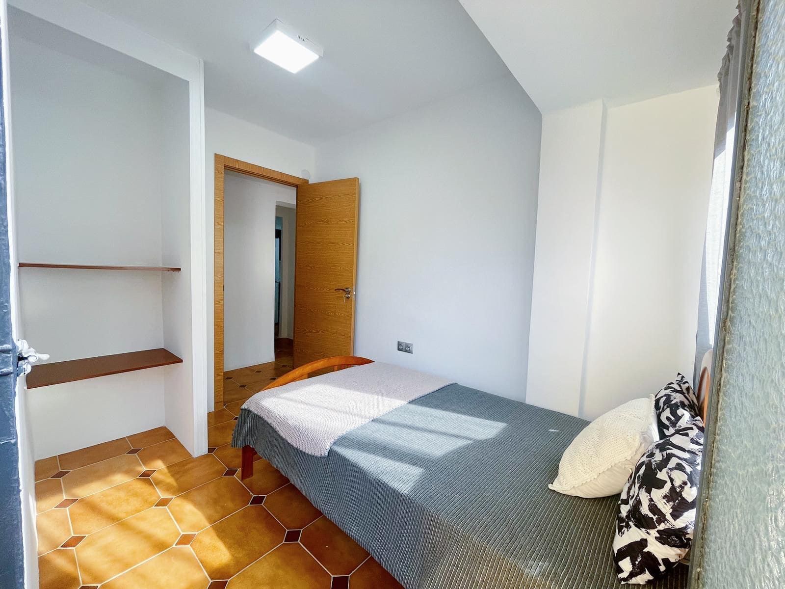 Pequeño dormitorio con cama individual, armario y luz natural.