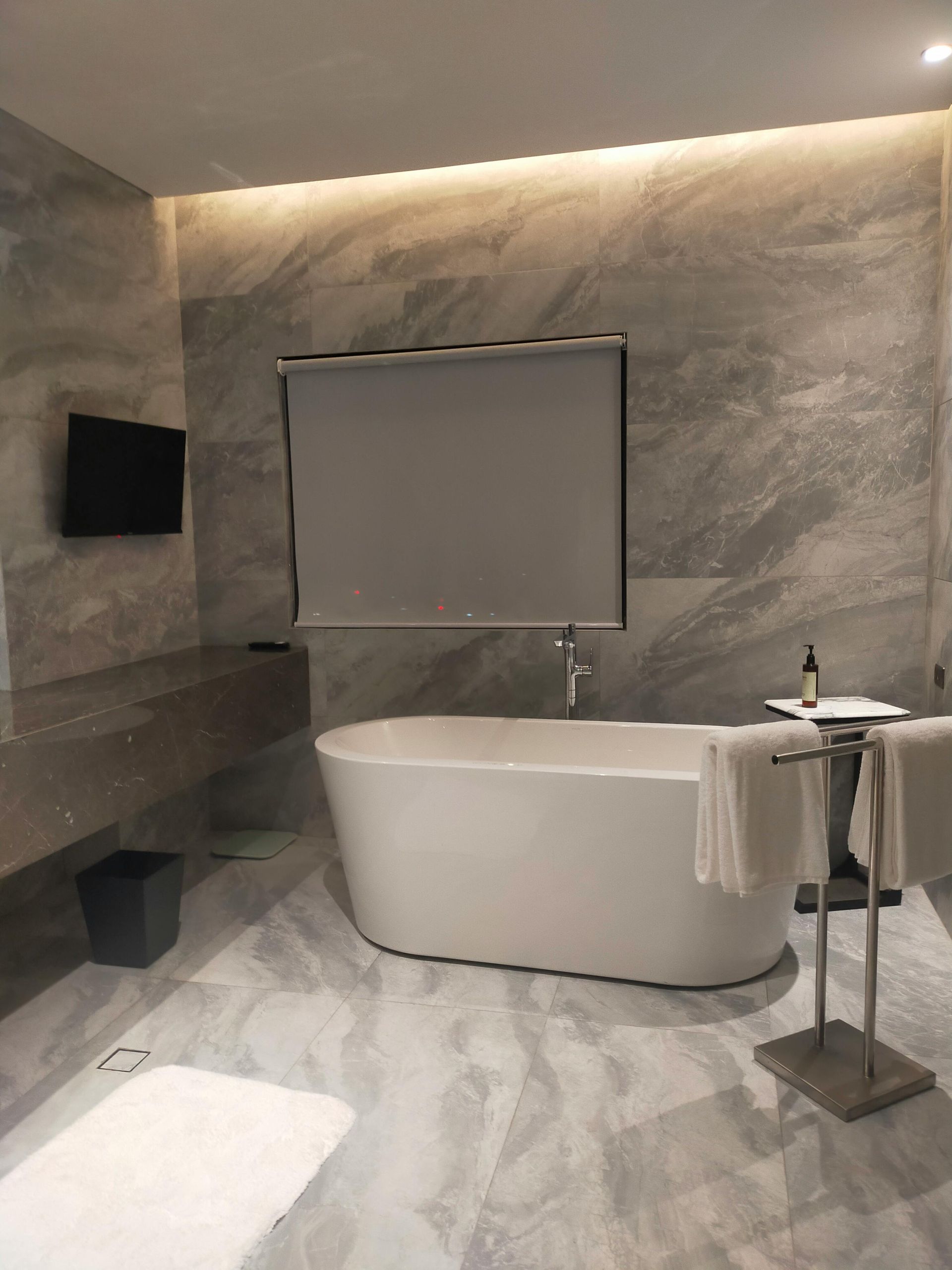 Baño con ducha de cristal, detalles de madera y lavabo blanco sobre estante de madera.