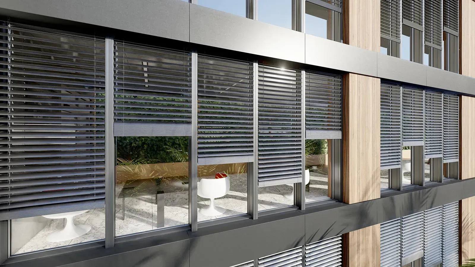 Außenansicht eines modernen Gebäudes mit grauen Jalousien vor den Glasfenstern, Balkon sichtbar.