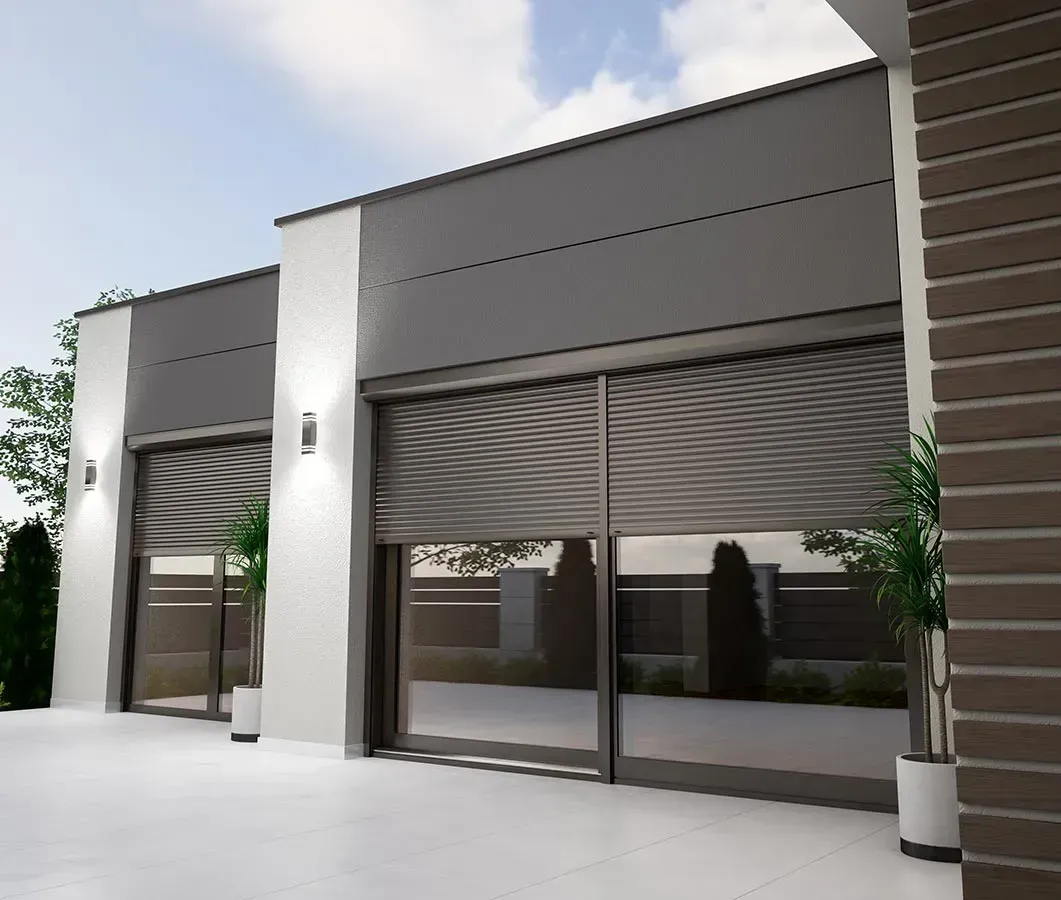 Modernes grau-weißes Gebäude mit Rolltoren und Topfpflanzen.