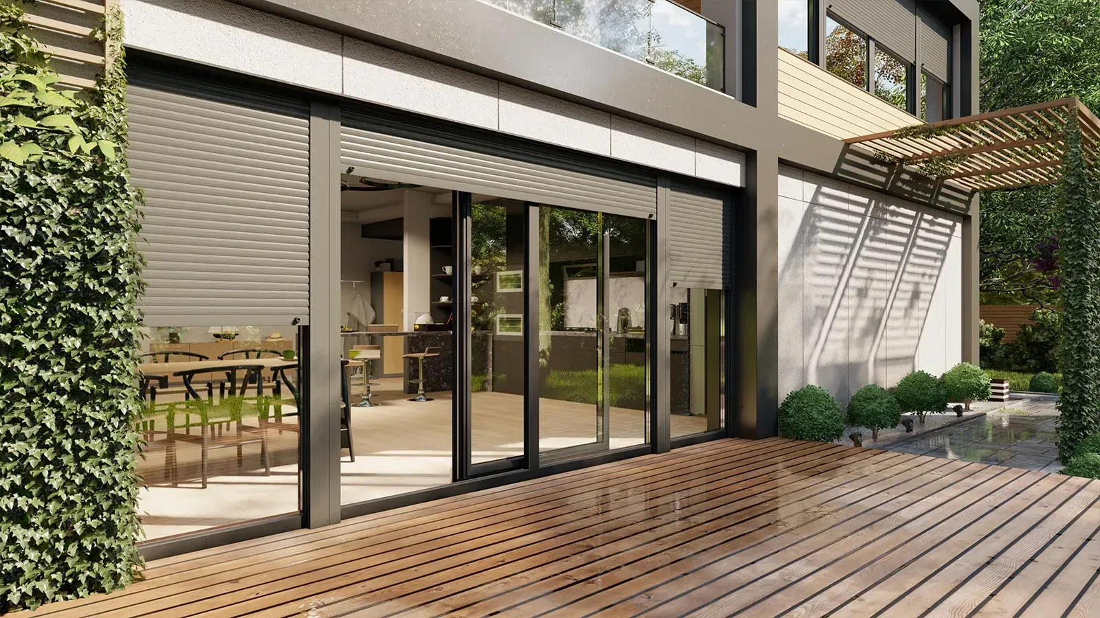 Modernes Haus mit Glasschiebetüren zu einer Holzterrasse; die Außenseite ist von grünen Pflanzen umgeben.