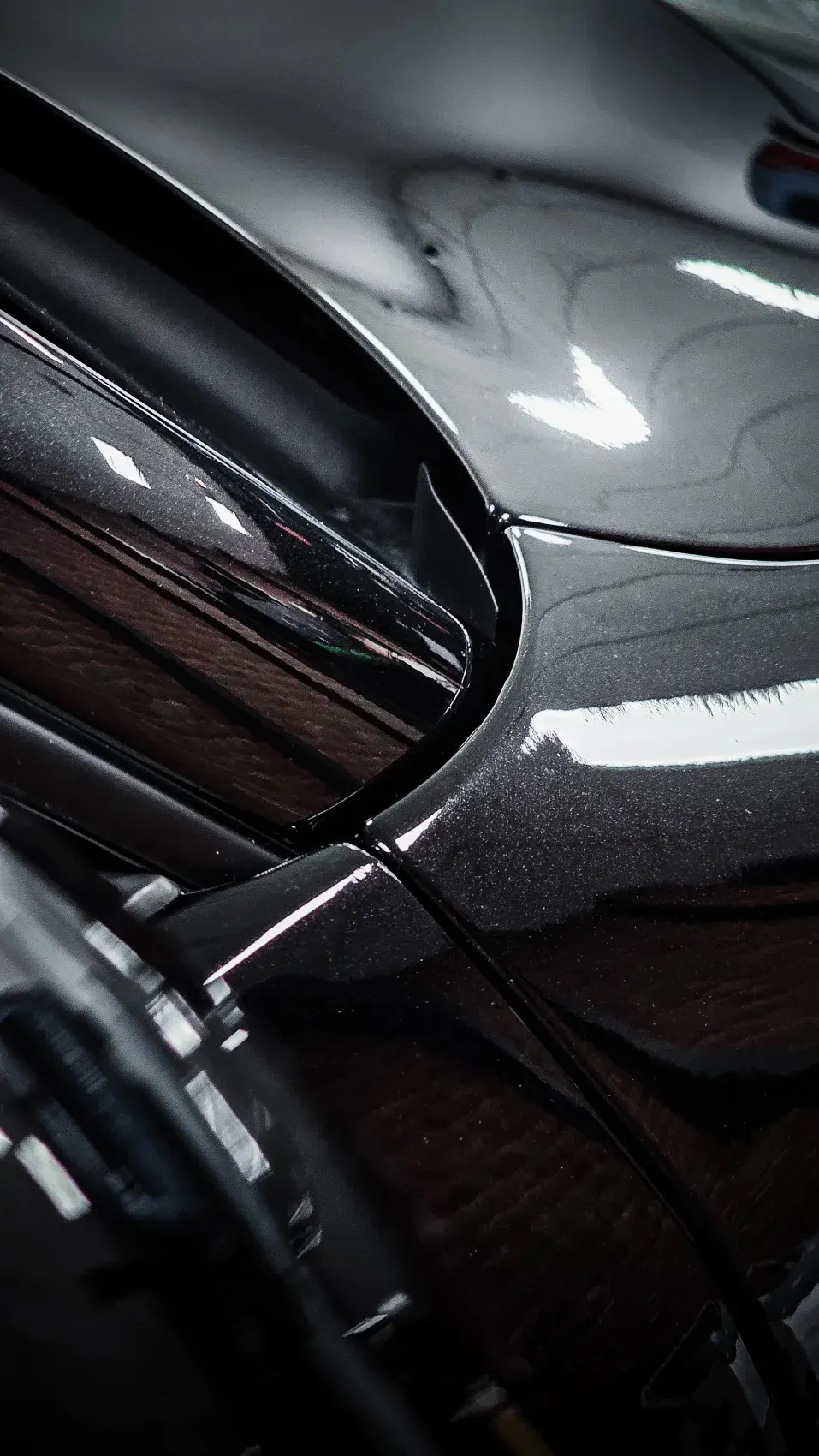 Primer plano de la carrocería de un automóvil negro elegante, que refleja la luz con un acabado brillante.