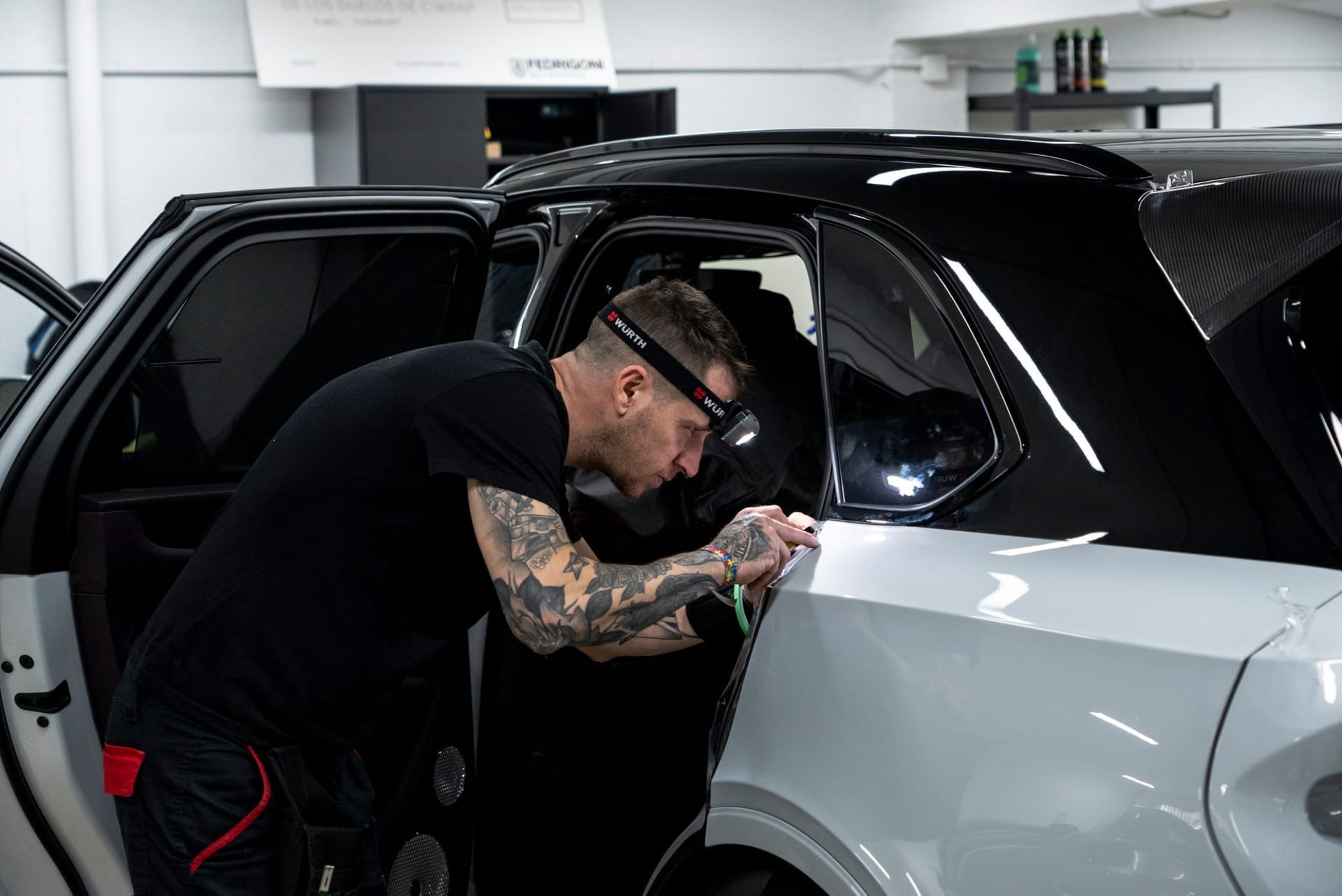 Una persona instalando láminas para tintar las ventanas de un automóvil en un garaje.