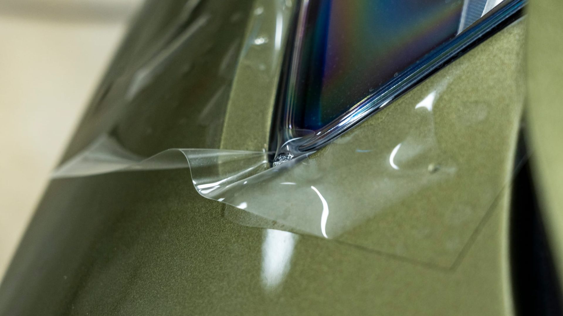 Película de plástico transparente aplicada a una superficie, con una esquina de un objeto visible detrás de ella.