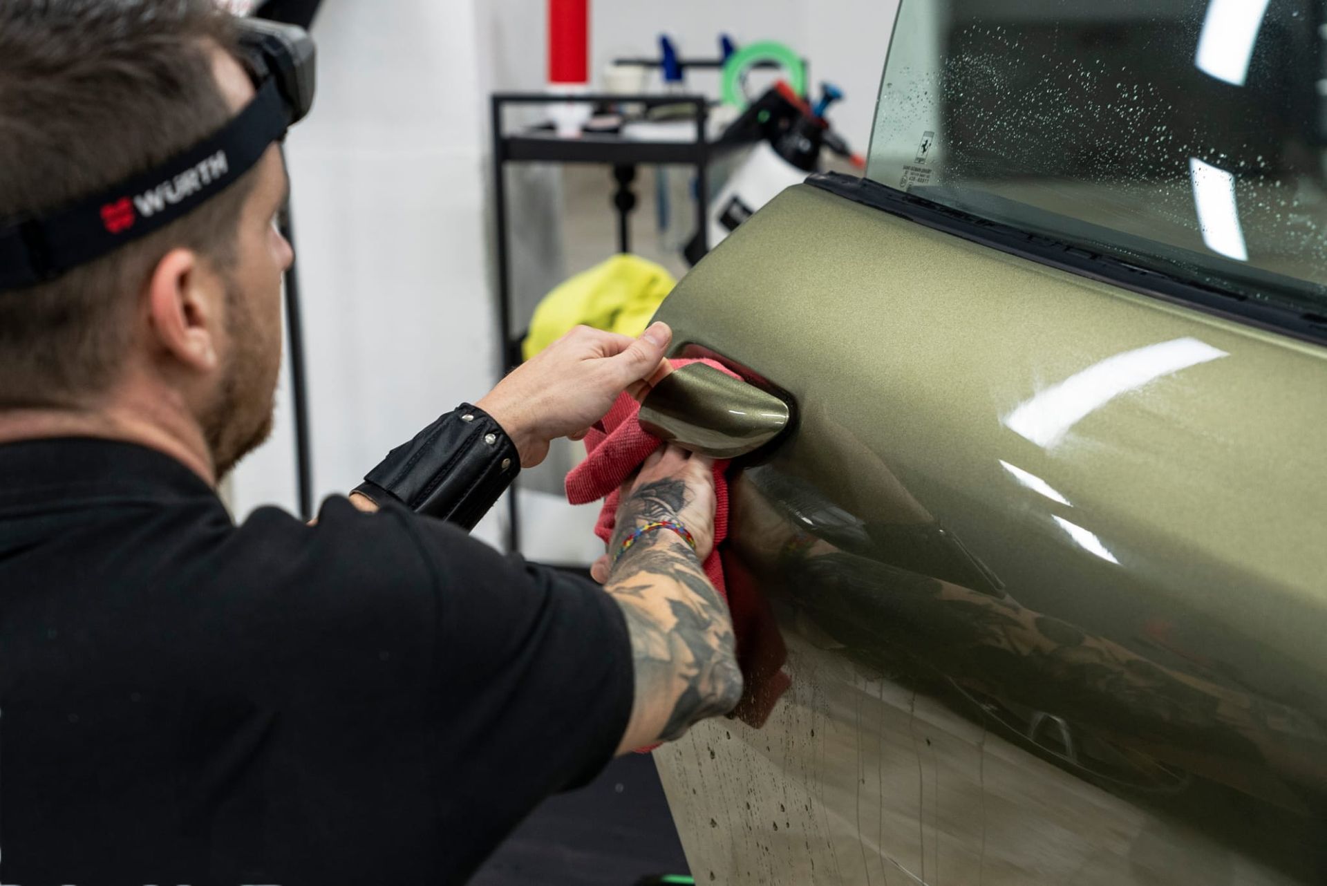 Una persona limpiando la manija de la puerta de un automóvil, preparándola para tintarla.