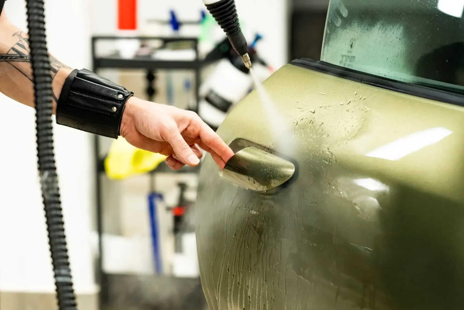 Persona limpiando con vapor la manija de la puerta de un automóvil