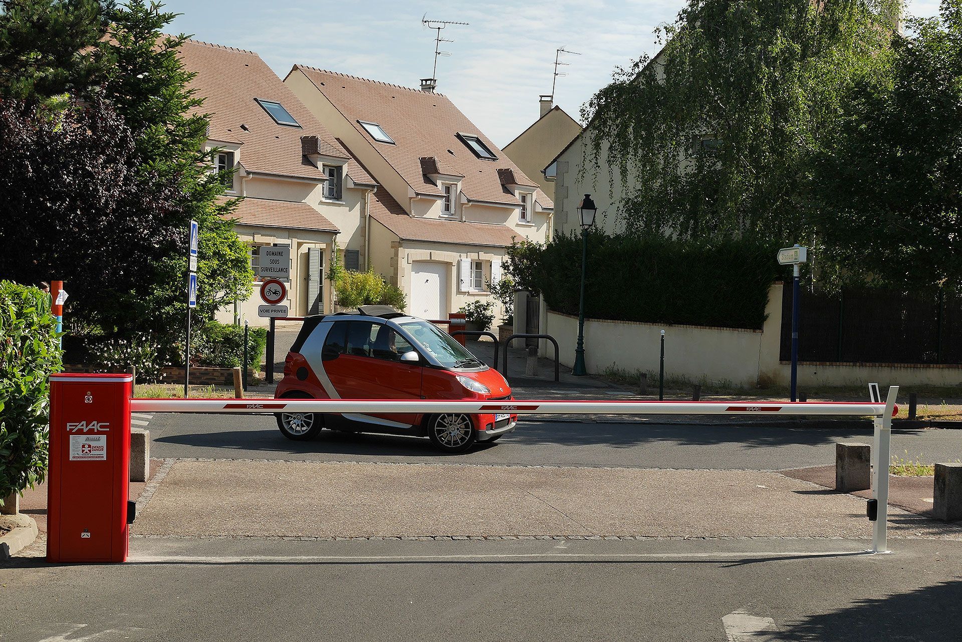 Une voiture rouge roulant derrière une barrière automatique