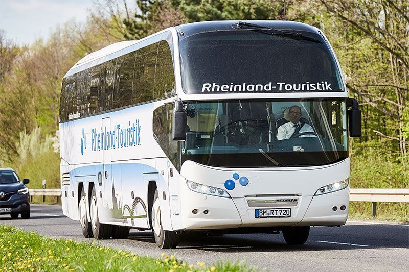 Ein Bus der Rheinland-Touristik fährt eine Straße entlang