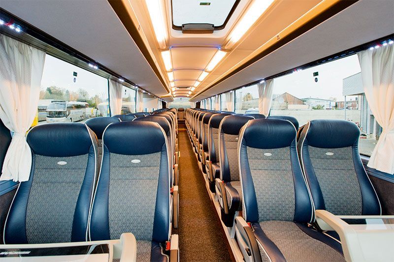 Das Innere eines Busses mit blauen Sitzen und weißen Vorhängen