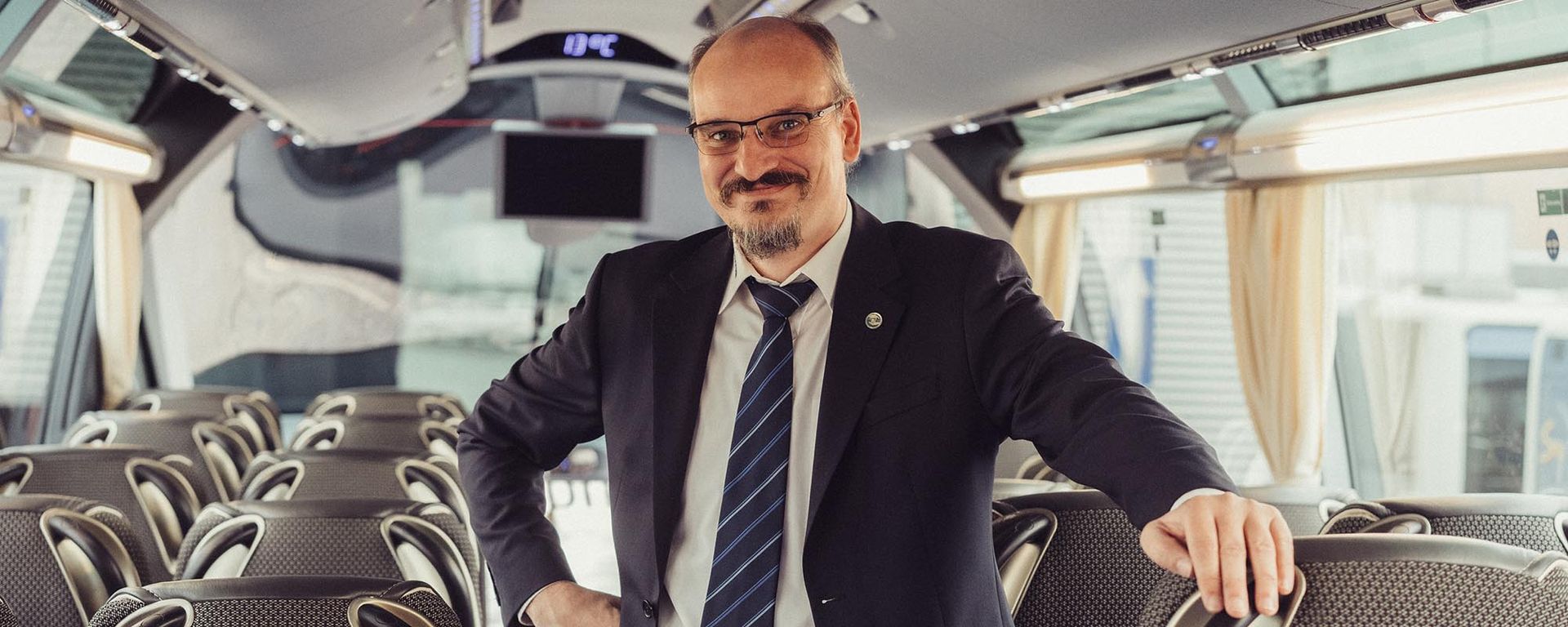 Ein Mann in Anzug und Krawatte steht in einem Bus