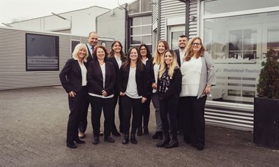 Eine Gruppe von Menschen posiert vor einem Gebäude für ein Foto.