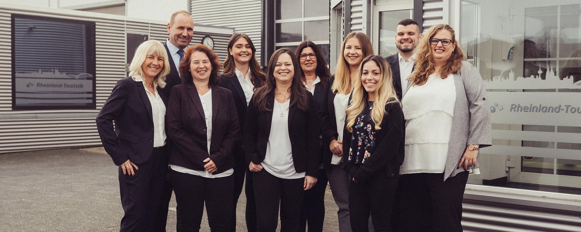 Eine Gruppe von Menschen posiert vor einem Gebäude für ein Foto.