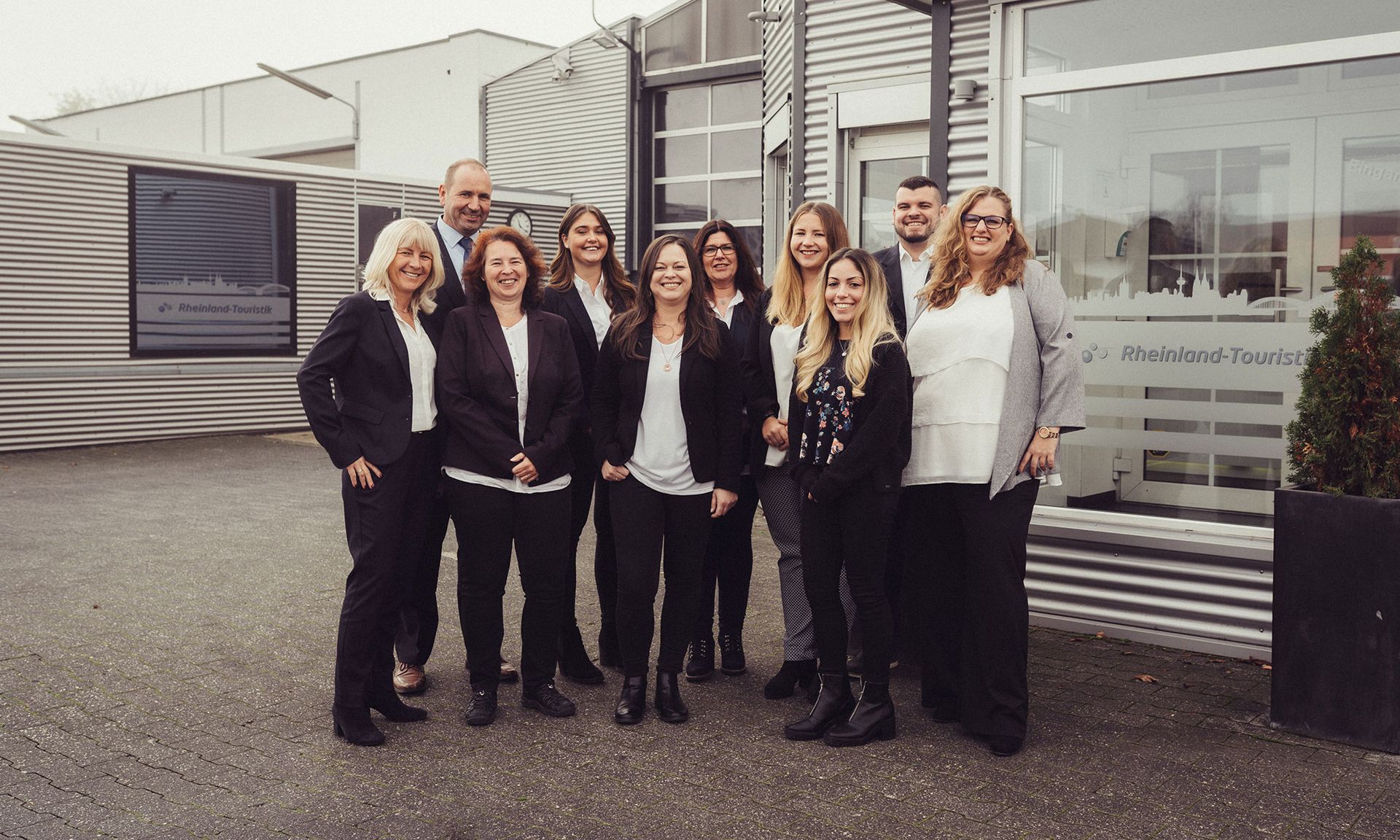 Eine Gruppe von Menschen posiert für ein Foto vor einem Gebäude