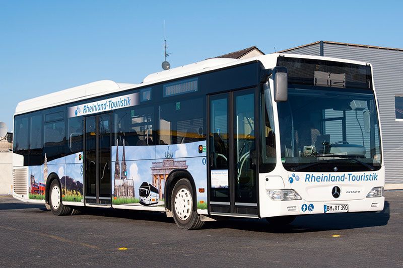 Ein blau-weißer Bus mit der Aufschrift „Rheinland Tourismus“ an der Seite