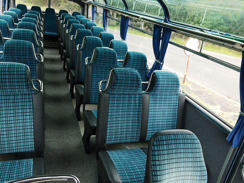 Das Innere eines Busses mit blauen Sitzen und blauen Vorhängen