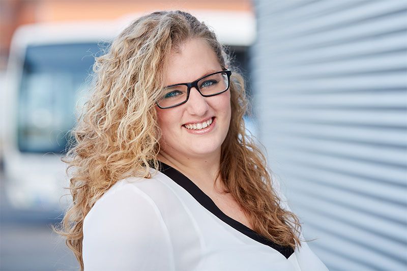 Eine Frau mit Brille und weißem Hemd lächelt in die Kamera