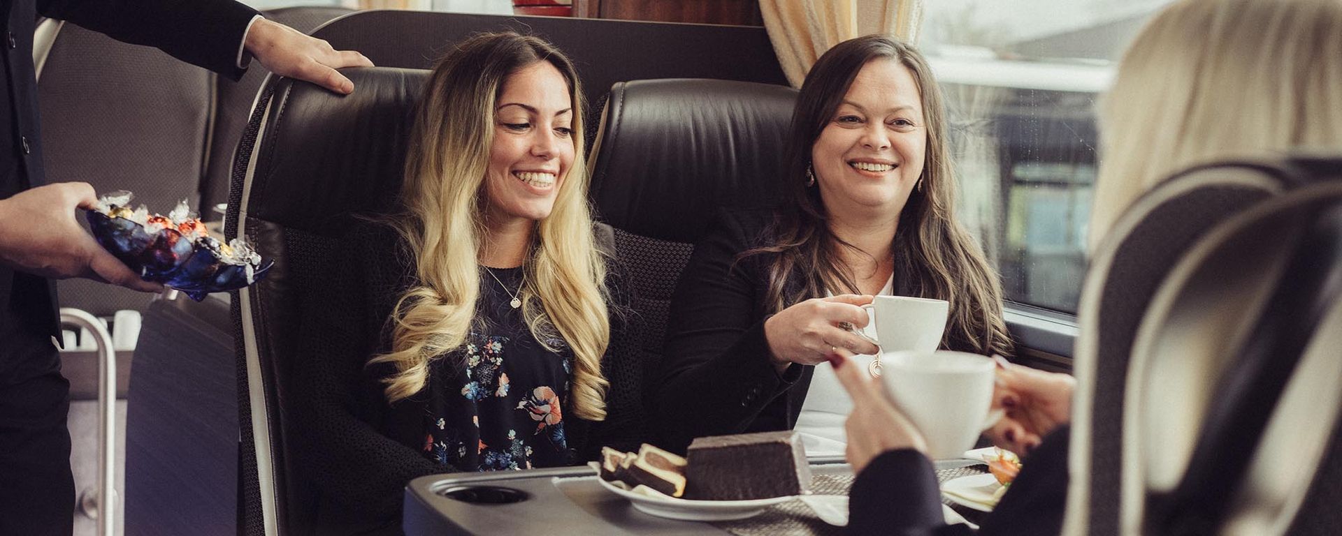 Eine Gruppe Frauen sitzt in einem Bus an einem Tisch und trinkt Kaffee.