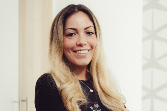 Eine Frau mit langen blonden Haaren lächelt in die Kamera.