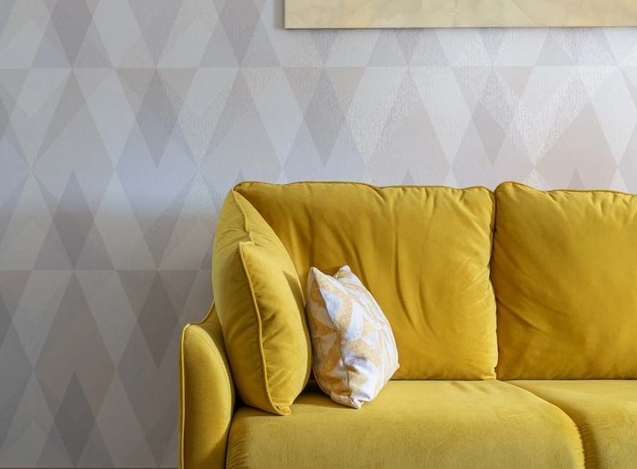 Canapé jaune devant un mur avec du papier peint