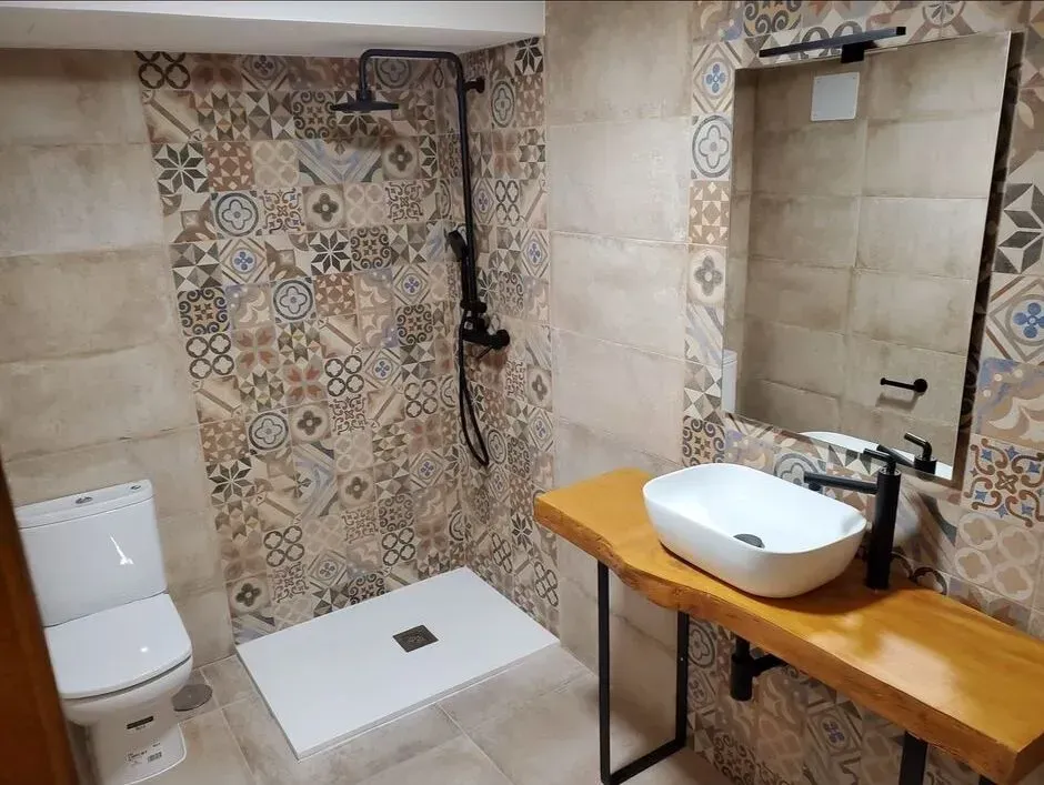 Un baño con inodoro, lavabo, espejo y ducha.