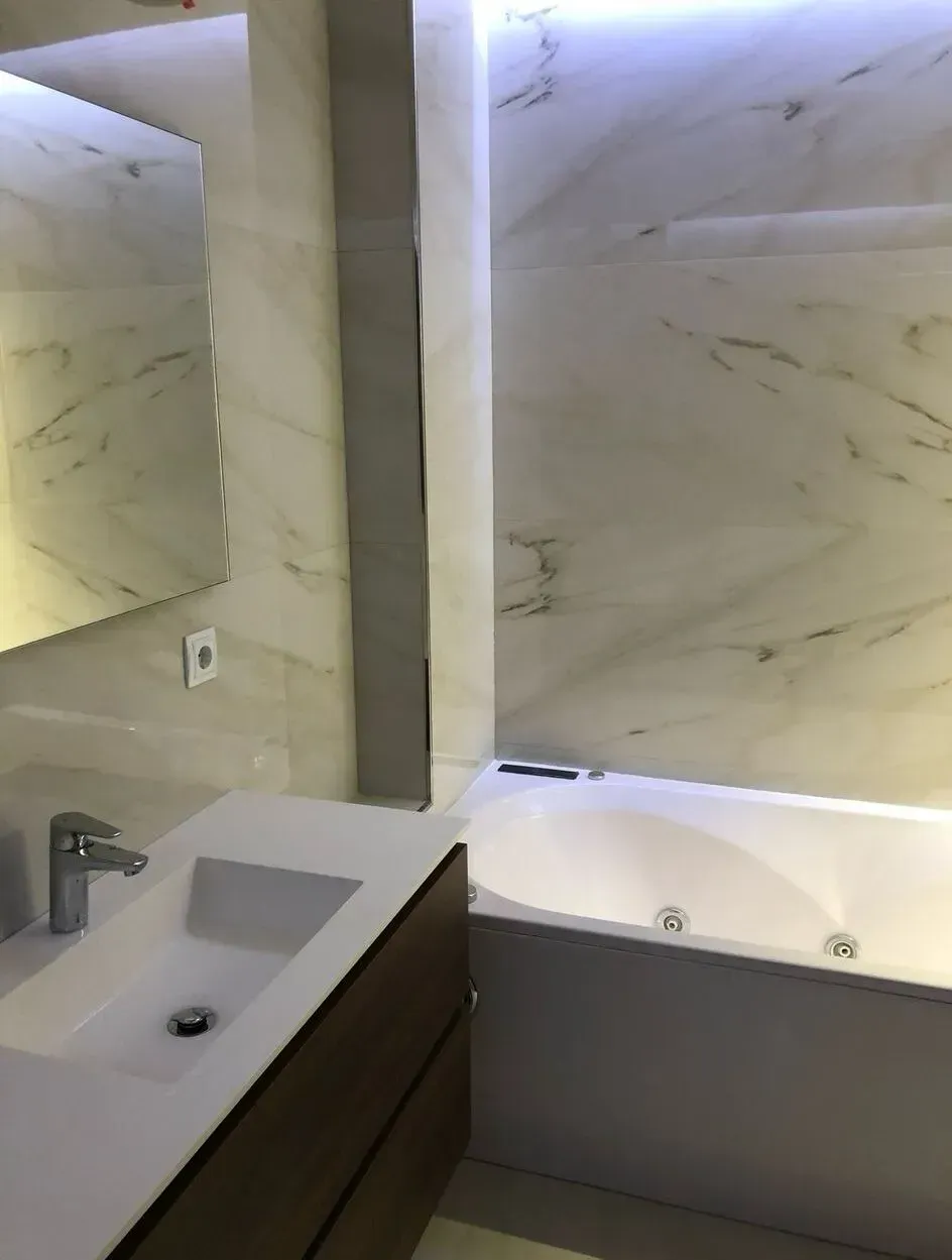 Un baño con lavabo, bañera y espejo.