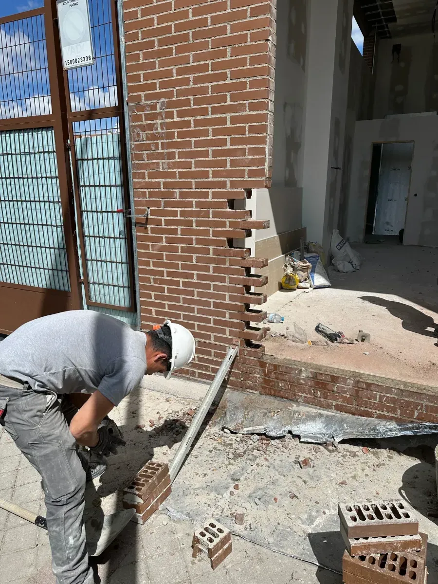 Un hombre que lleva un casco está trabajando en una pared de ladrillos.