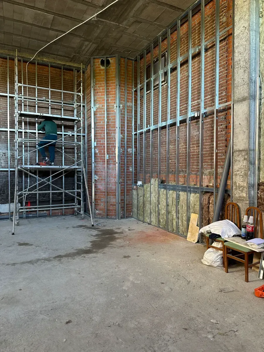 Un hombre está de pie sobre un andamio en un edificio en construcción.