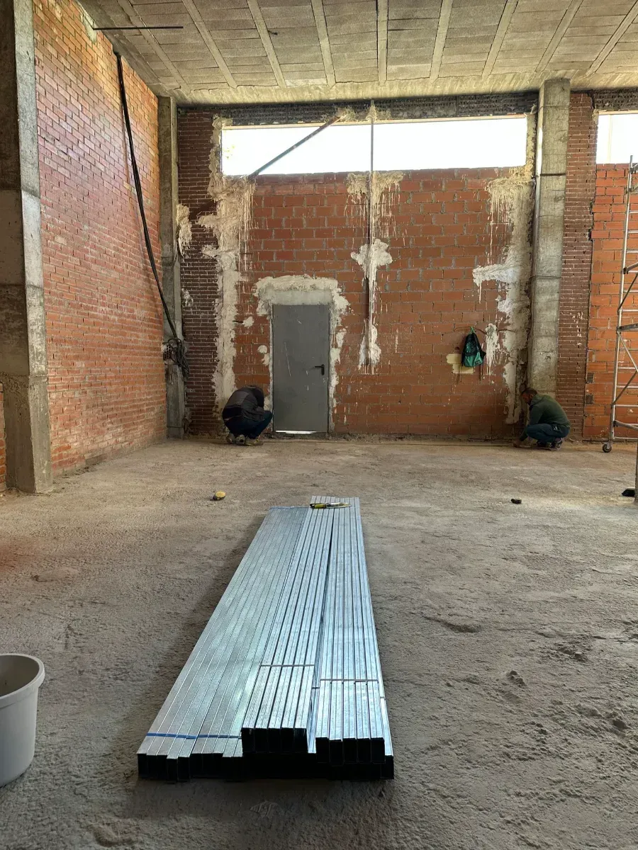 Una gran habitación vacía con una pared de ladrillos y una puerta.