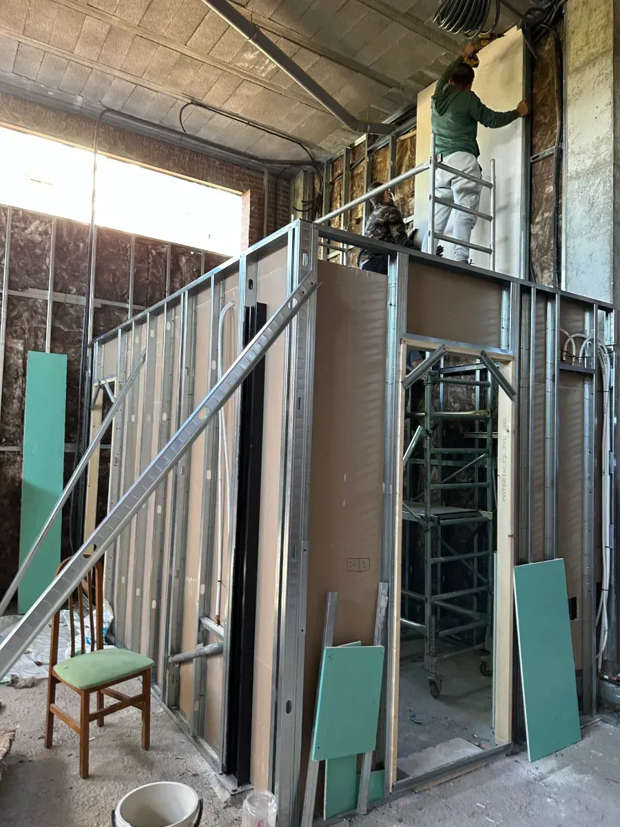 Un hombre está pintando una pared en un edificio en construcción.