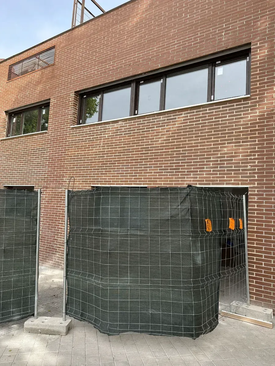 Un edificio de ladrillo con una valla delante.