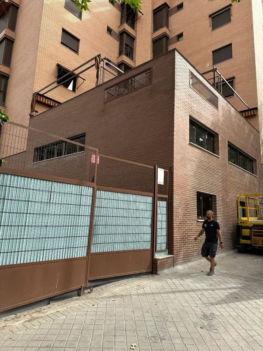 Un hombre camina por una acera frente a un edificio de ladrillos.