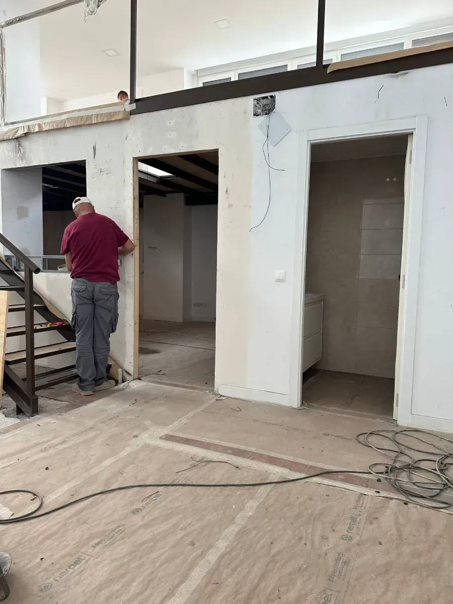 Un hombre está de pie en una habitación vacía al lado de una escalera.