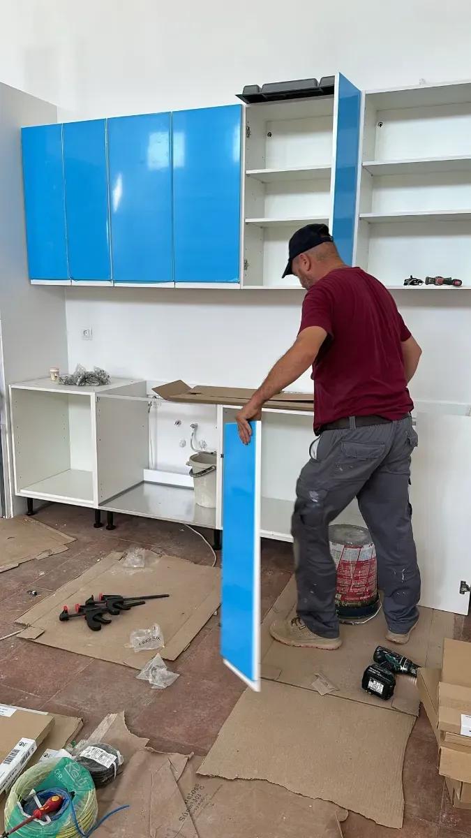 Un hombre está trabajando en una cocina con gabinetes azules.