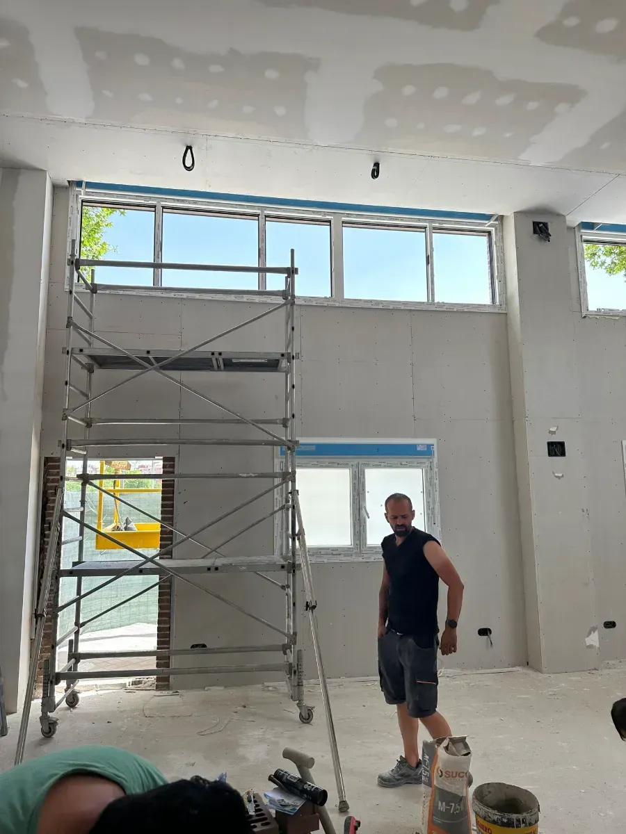 Un hombre está de pie en una habitación con un andamio al fondo.