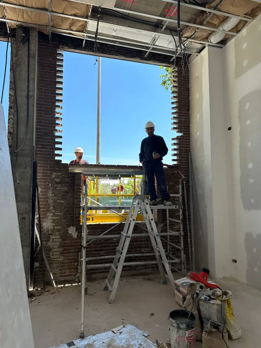Un hombre está de pie en una escalera frente a una ventana grande.