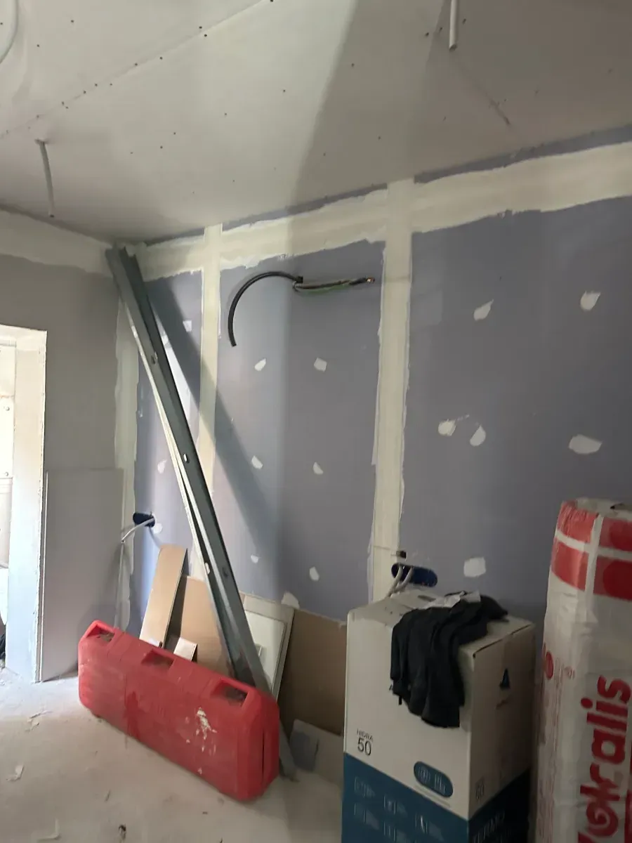 Una habitación que está siendo remodelada con cajas en el piso y una pared gris.