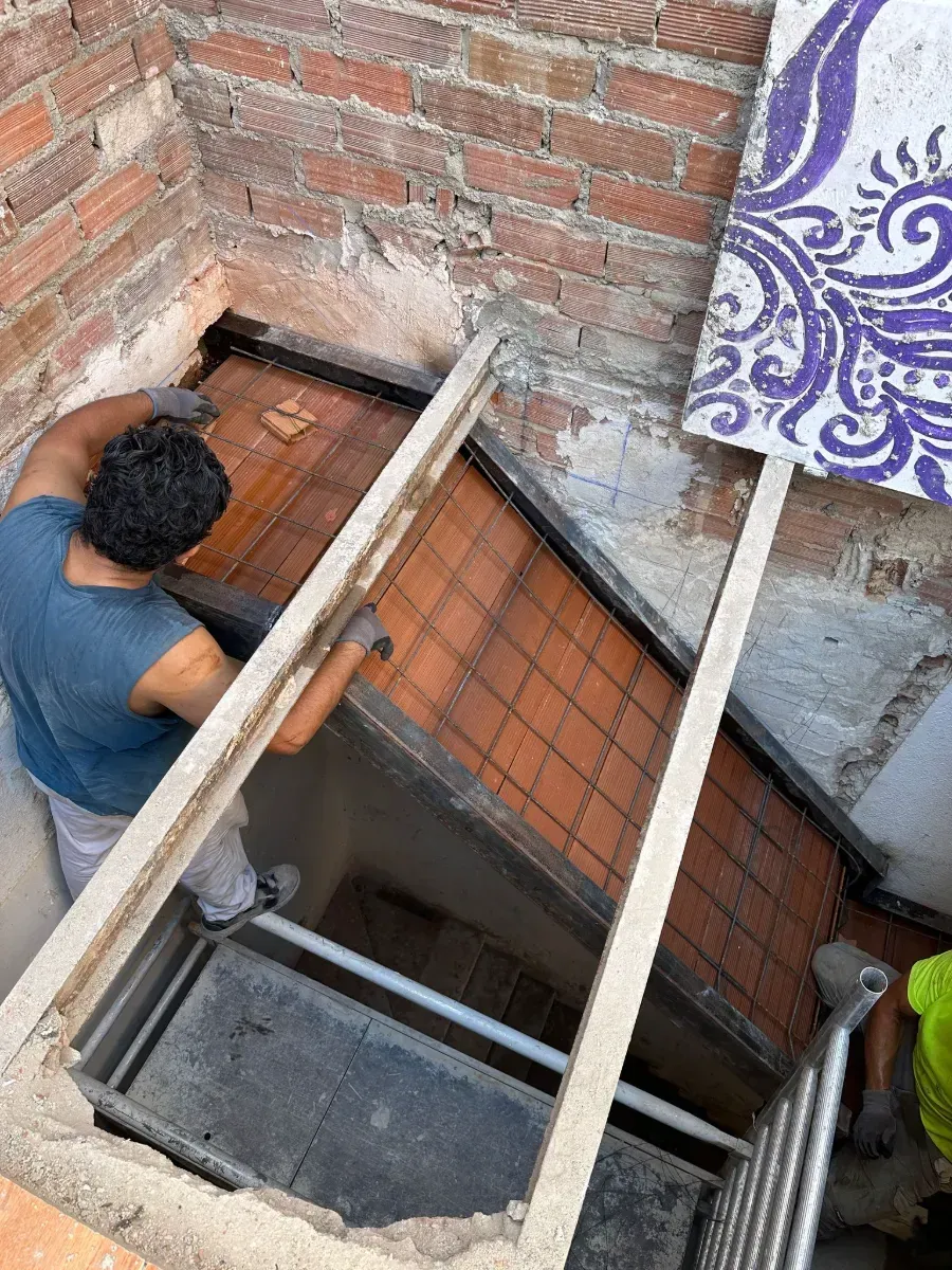 Un hombre está trabajando en una escalera en un edificio de ladrillos.