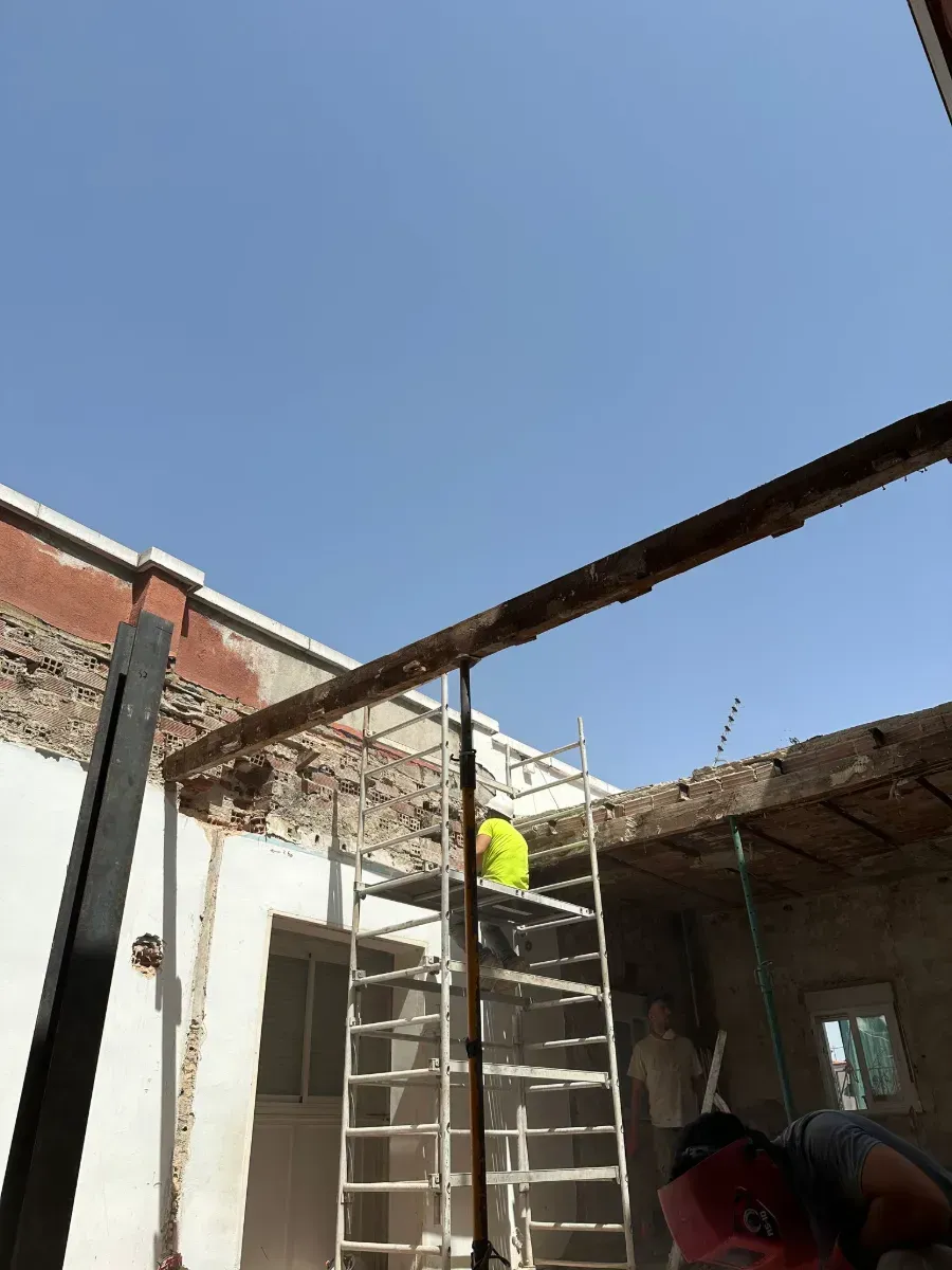 Un hombre está de pie en un andamio frente a un edificio.