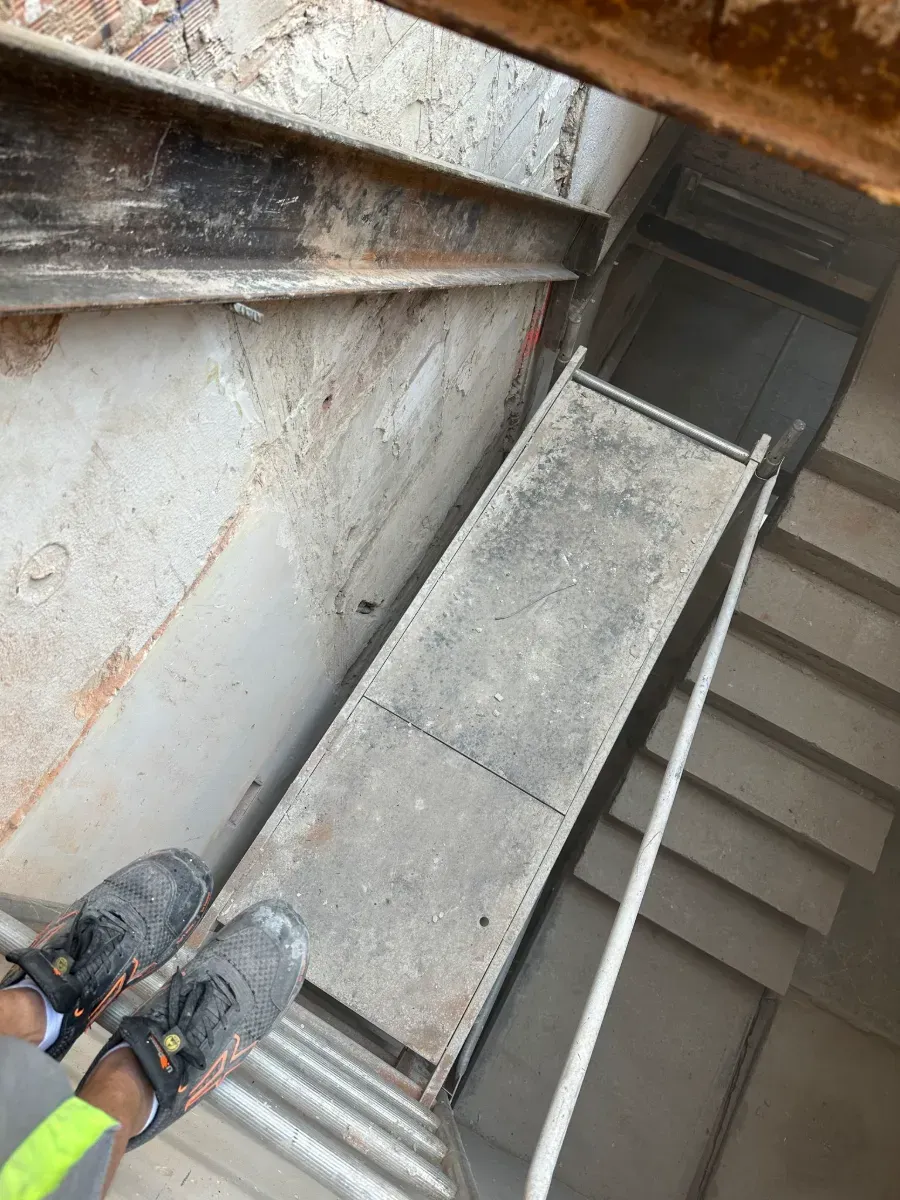 Una persona está de pie sobre un andamio al lado de un conjunto de escaleras.