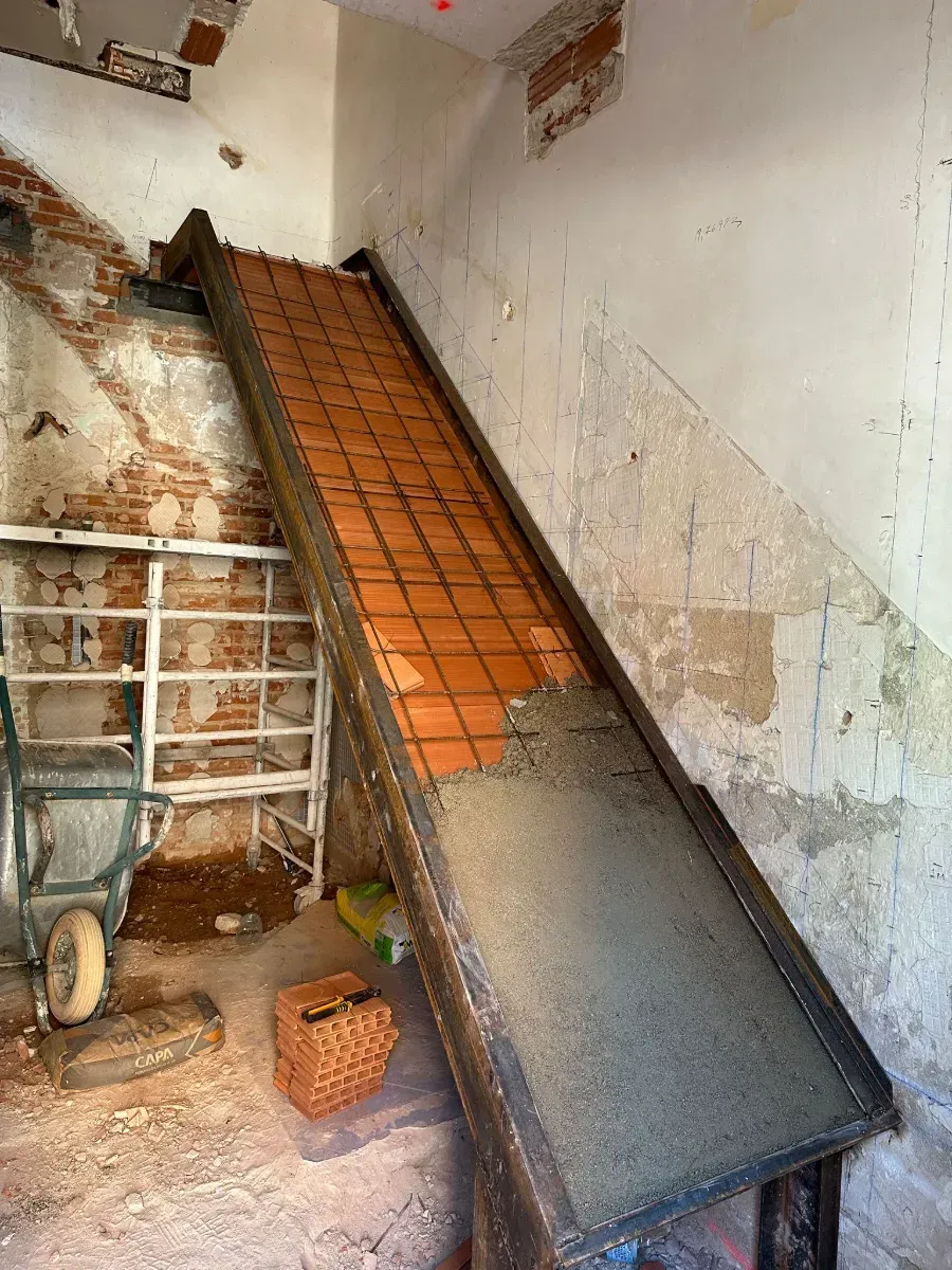 Se está construyendo una escalera en una habitación con una pared de ladrillos.