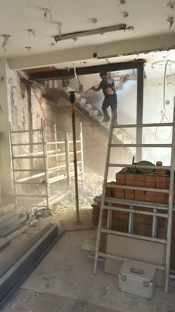 Un hombre está de pie en una escalera en una habitación en construcción.