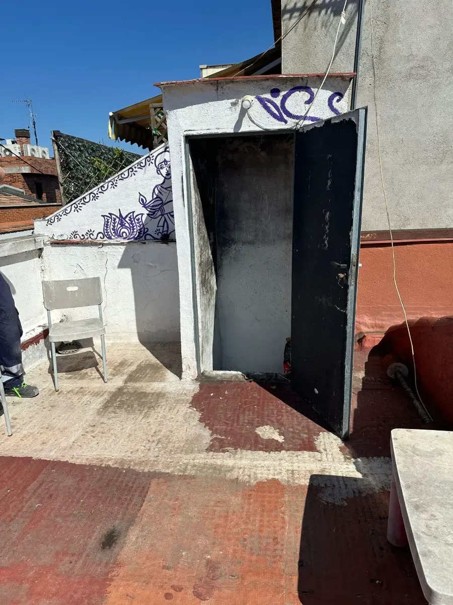 Una silla está sentada en un patio al lado de una puerta con un grafiti en ella.