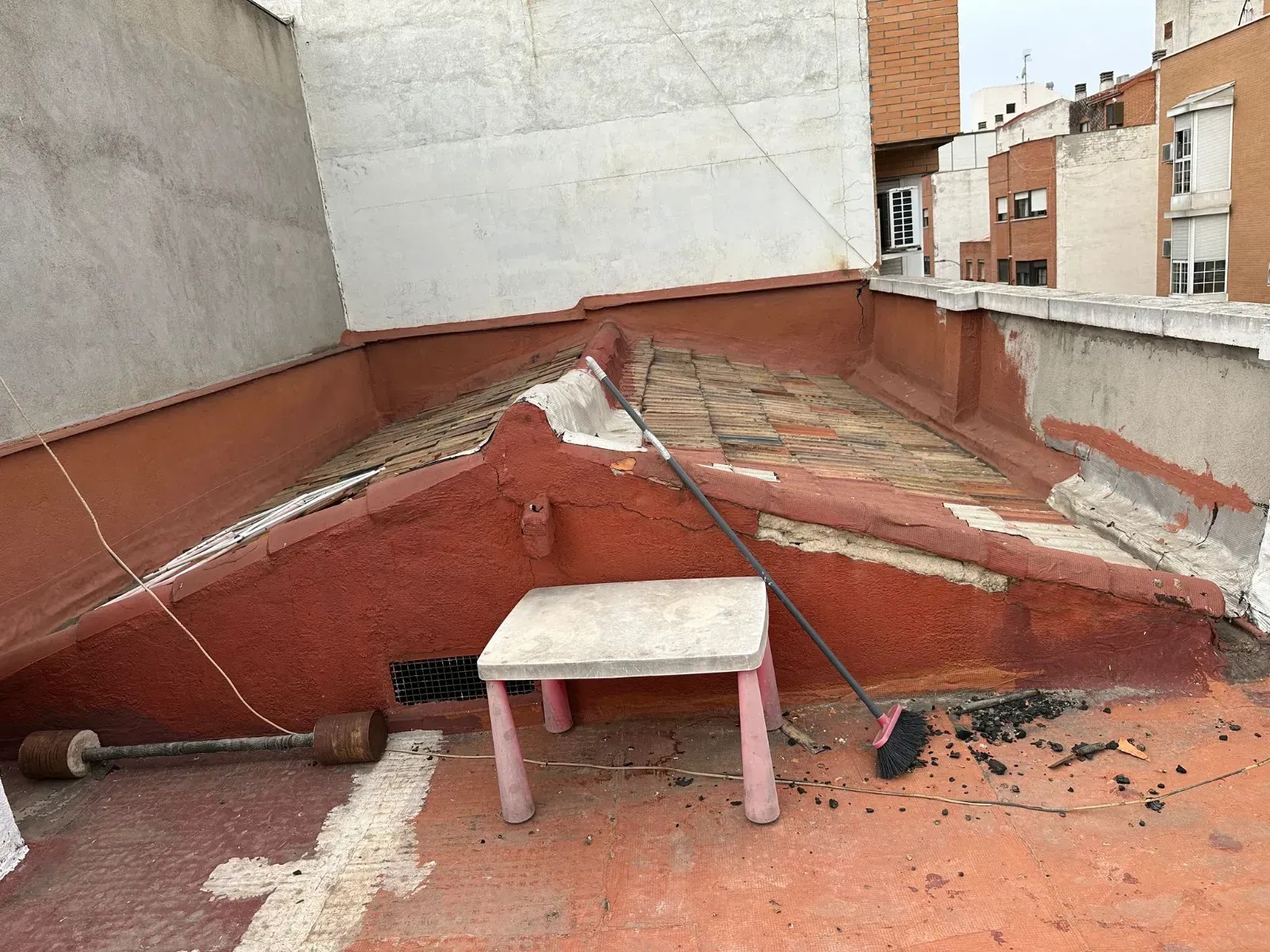 Hay una mesa pequeña y una escoba en el techo.