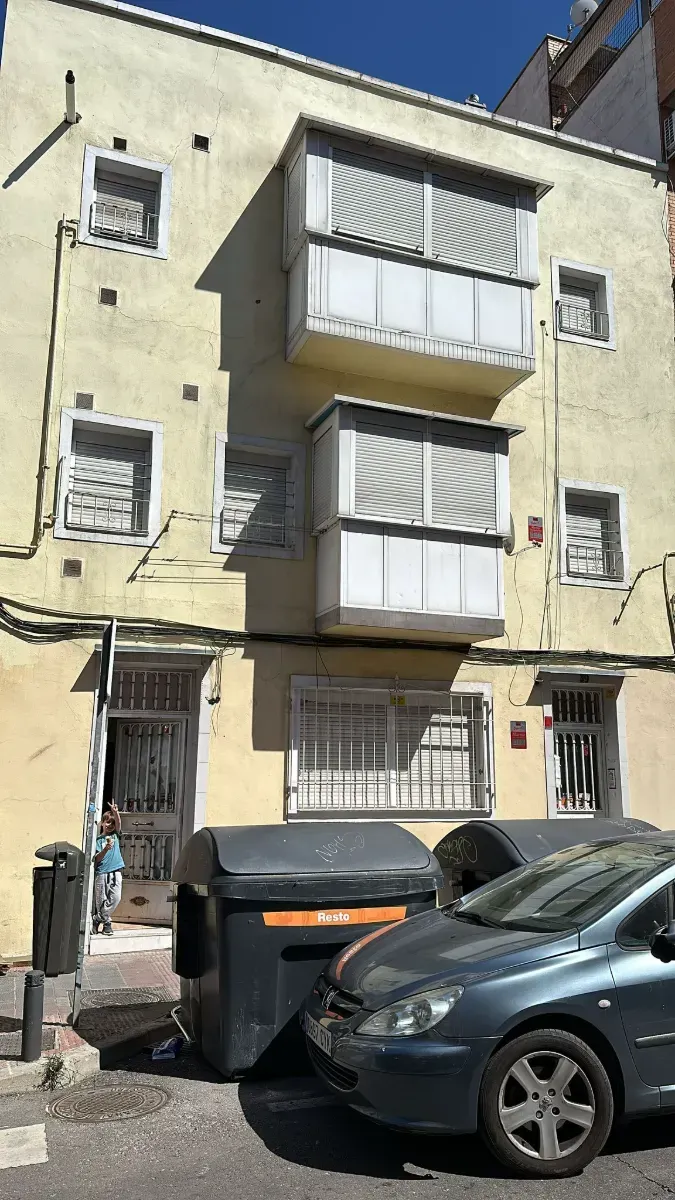 Un coche está aparcado delante de un edificio amarillo.