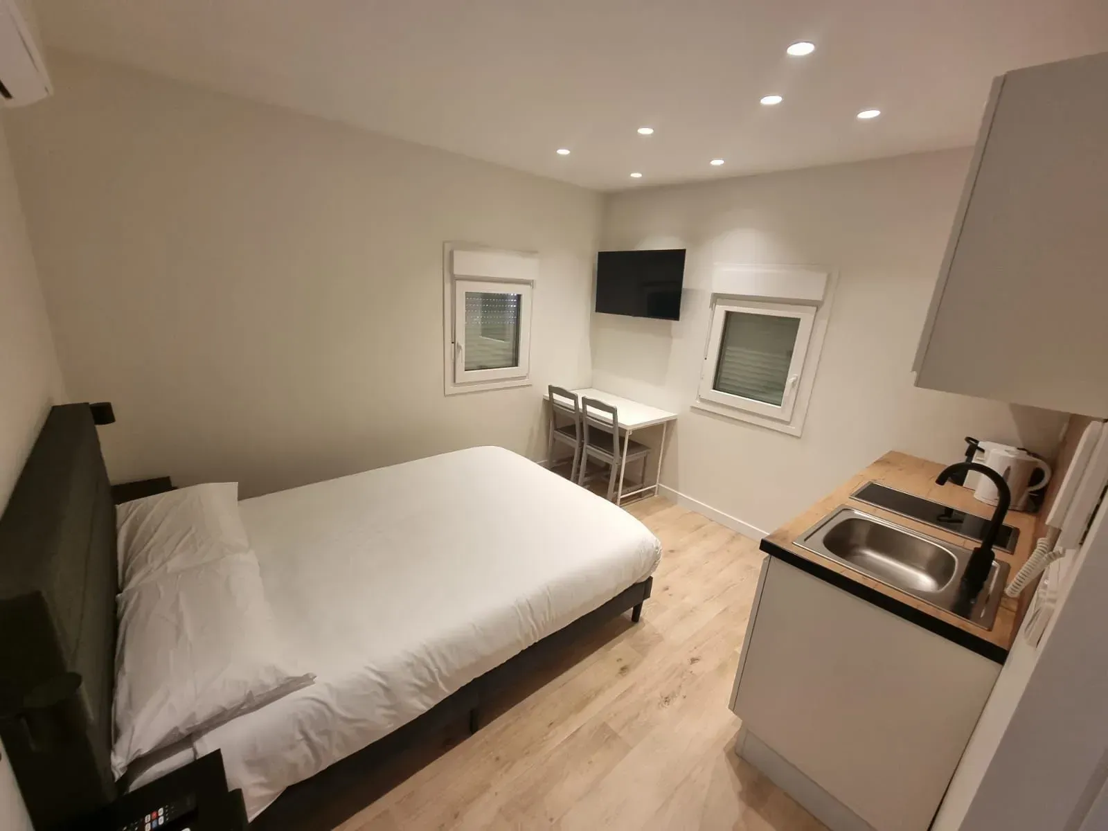 Un dormitorio con cama, escritorio, lavabo y televisión.