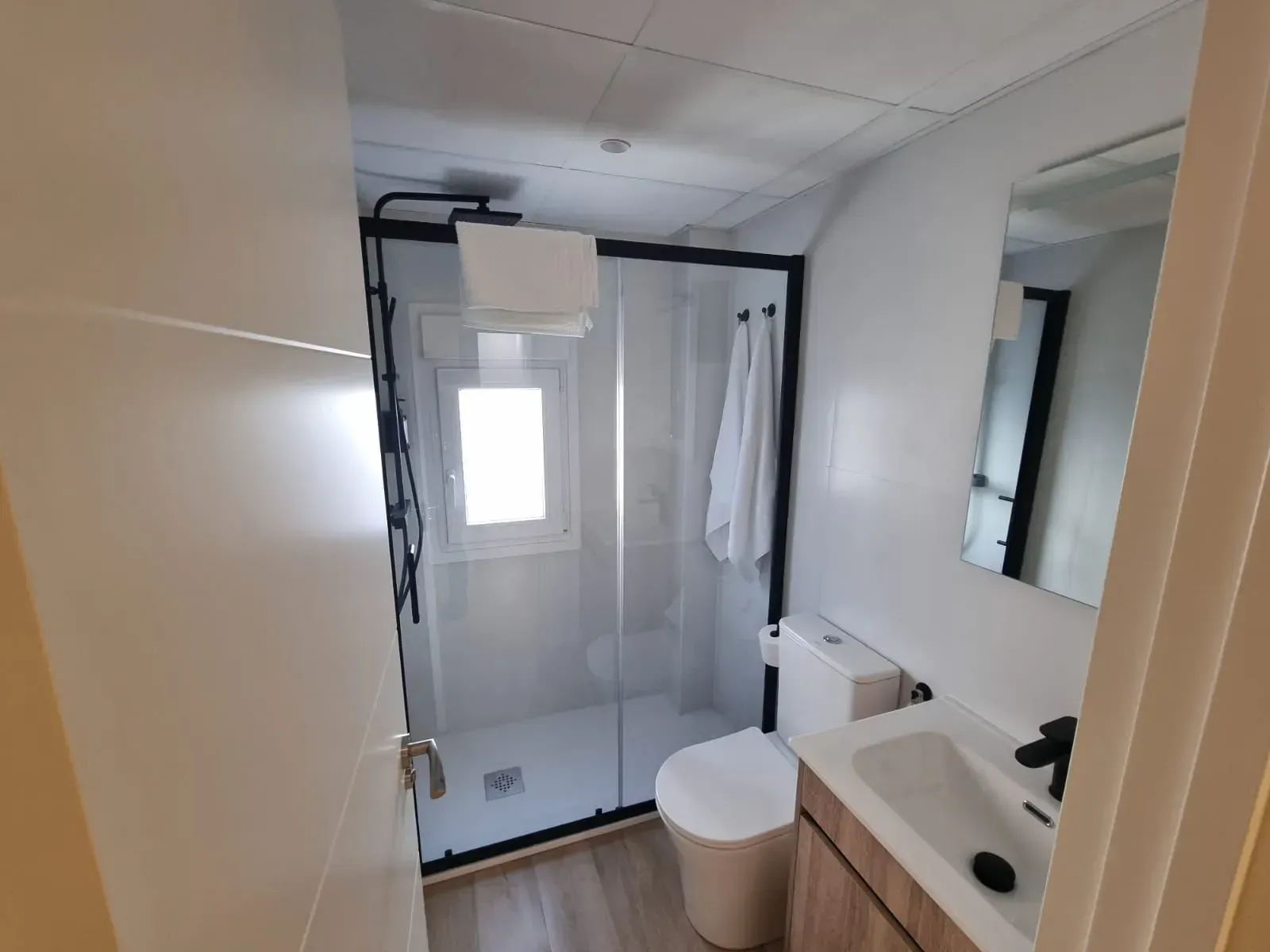 Un baño con inodoro, lavabo, ducha y espejo.